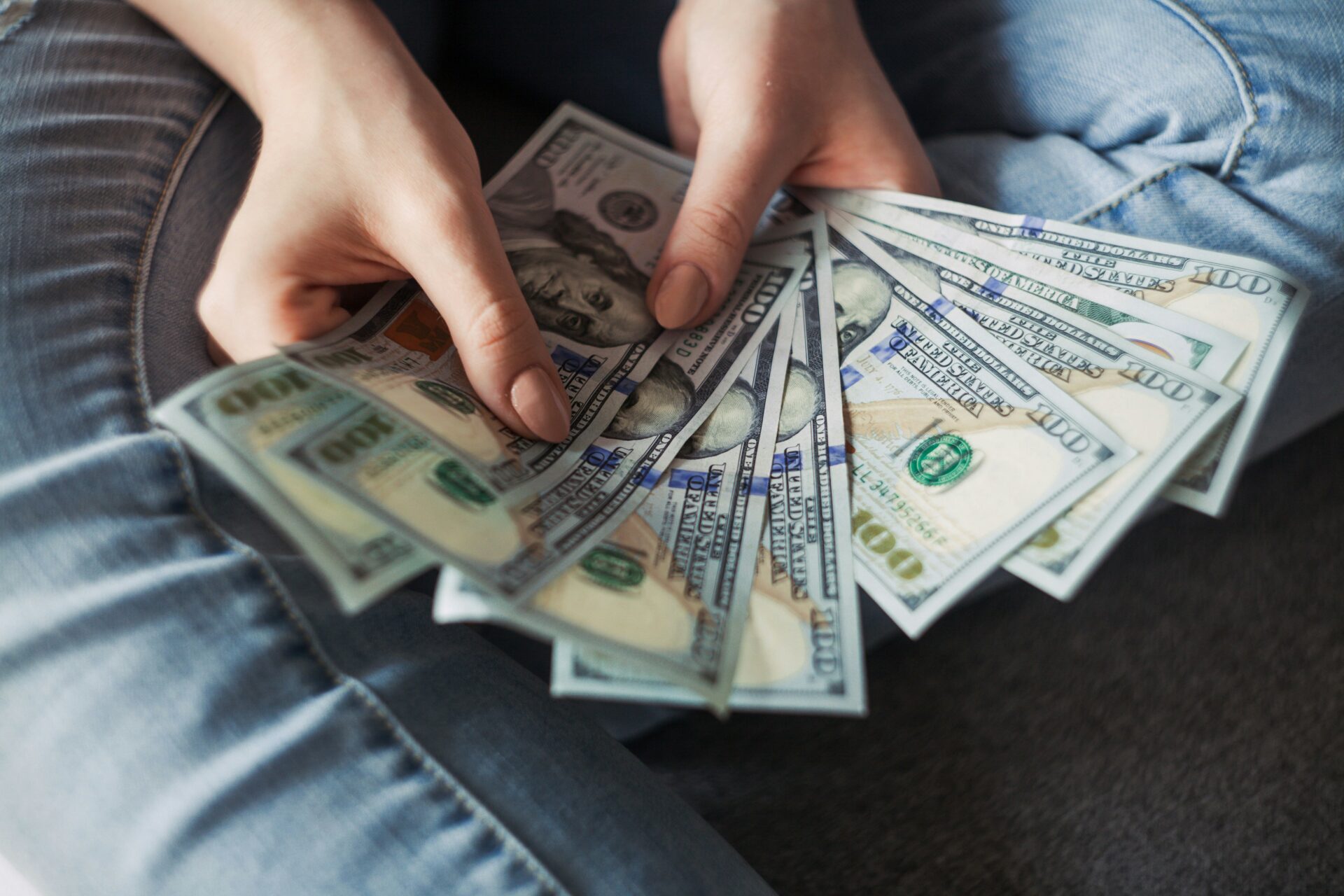 Person holding several hundred dollar bills in their hands.