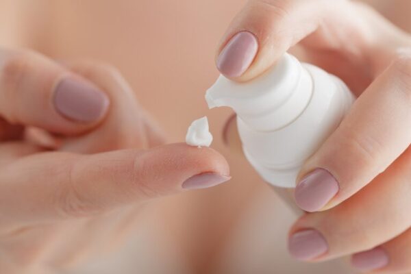 Person applying cream onto their finger from a tube.