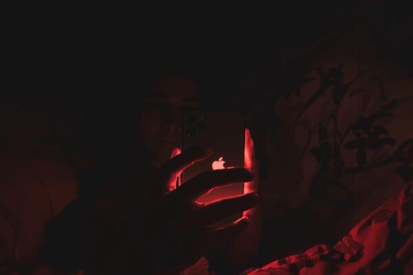 Person using iPhone with red light in dark bedroom