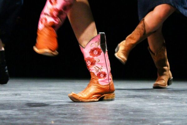 The History of Line Dancing Dancers showcasing colorful cowboy boots on stage lin