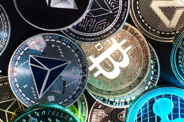 Various cryptocurrency coins including Bitcoin, Ethereum, Ripple, and TRON displayed in a colorful, close-up arrangement