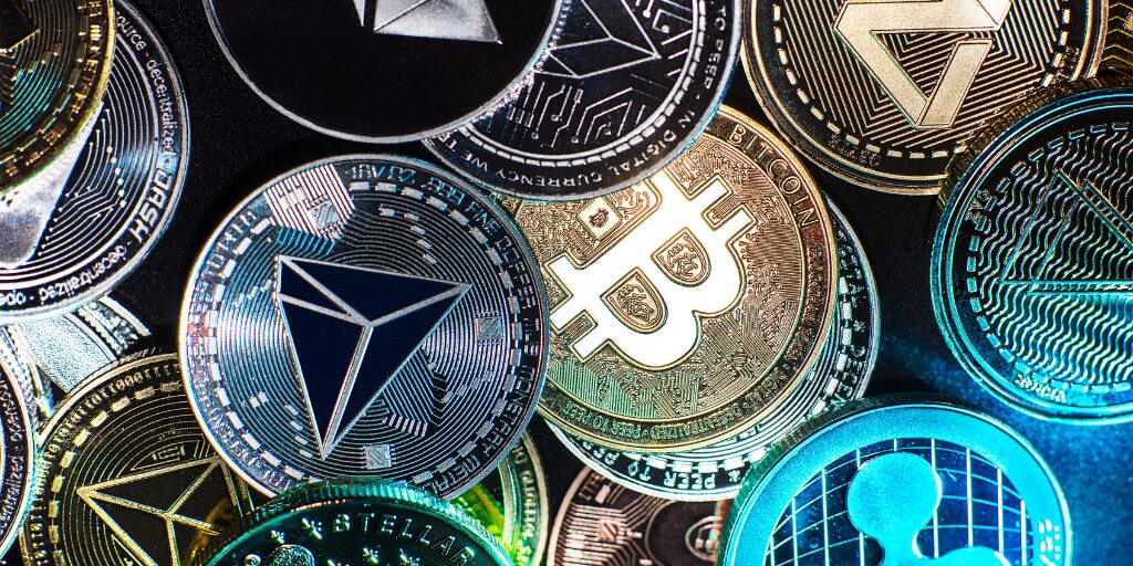 Various cryptocurrency coins including Bitcoin, Ethereum, Ripple, and TRON displayed in a colorful, close-up arrangement