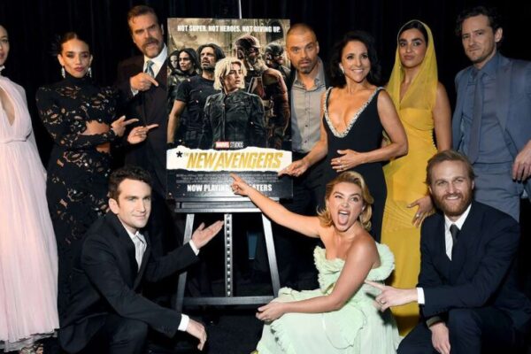 Cast members of the Marvel film posing around a poster renamed ‘The New Avengers,’ pointing and smiling at the new title reveal.