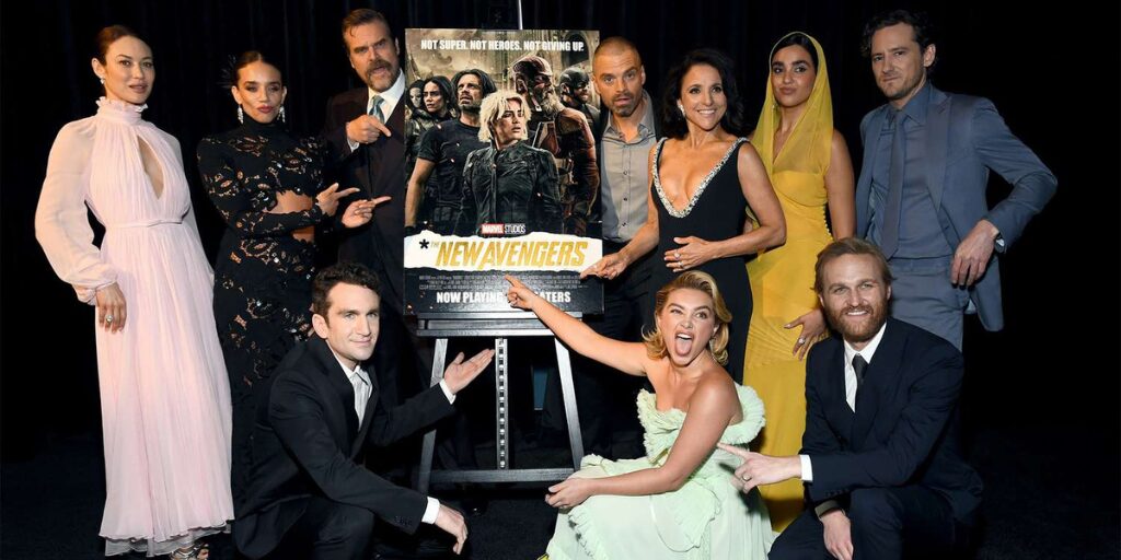Cast members of the Marvel film posing around a poster renamed ‘The New Avengers,’ pointing and smiling at the new title reveal.