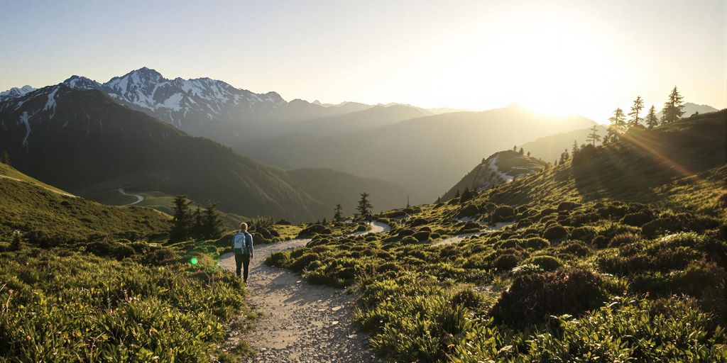 Traveler walking on mountain path at sunrise