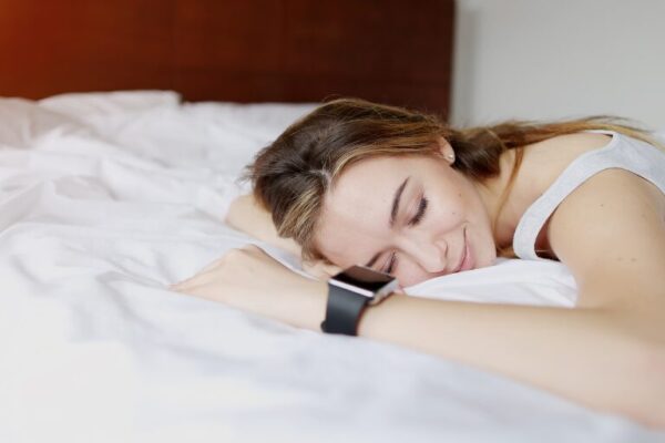 Woman peacefully sleeping on a bed, wearing a smartwatch.